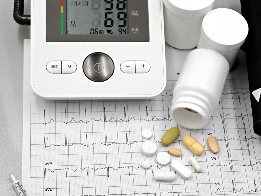Medical setup featuring blood pressure monitor, pills, syringes, and ECG printout for healthcare themes.